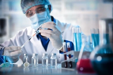 Virologist filling a syringe researching vaccine in laboratory bench