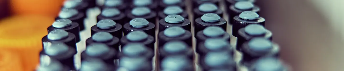 Close-up of neatly arranged small laboratory vials with black caps stored in a refrigerated unit.