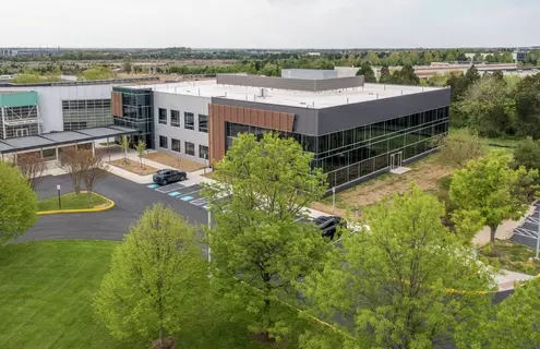 Aerial view of the ATCC headquarters building surrounded by landscaped greenery and parking areas under a clear blue sky.