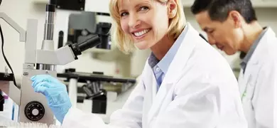 Female Scientists Using Microscopes In Laboratory