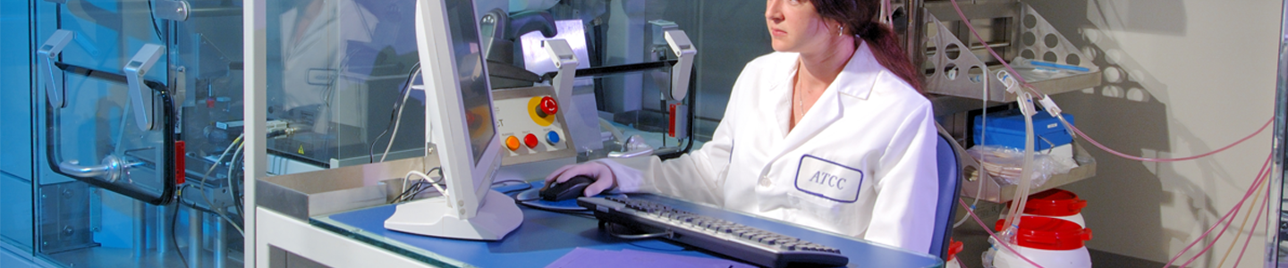 Female ATCC scientist sitting at computer, looking at monitor, next to lab equipment.