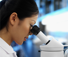 Profile of female scientist looking into microscope.