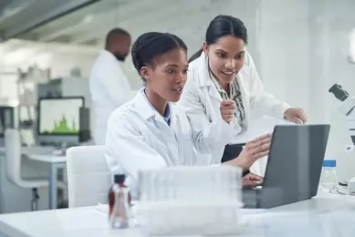 Two female scientist in front of a computer in a lab