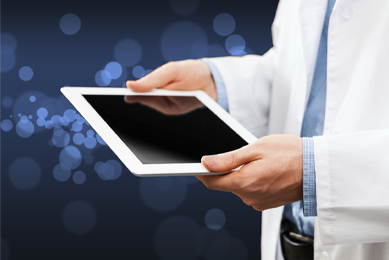 Man in a white lab coat holding a white-framed iPad in his hands.