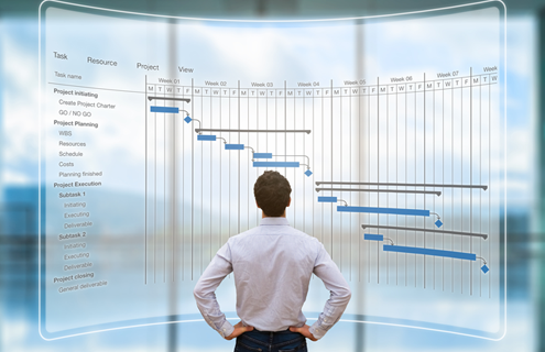 A man standing in front of a huge project planning chart on a screen.