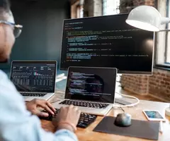 Programmer typing out code on monitors.