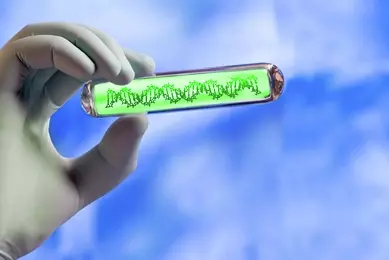 Gloved hand holding a glass tube with green DNA inside a top a sky withg clouds backgrounbd