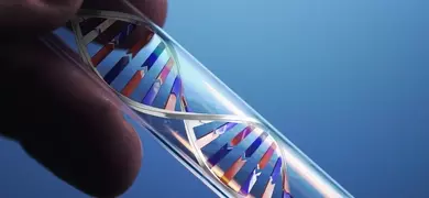 Fingers holding a test tube containing a silver, red, and blue DNA double helix.