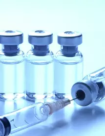 Close-up of six small medical vials standing in a row filled with liquid medicine. One bottle is ready for syringe injection.