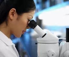Female Scientist looking through a microscope.
