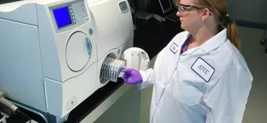 Female ATCC scientist opening door of Vitek2 microbial identification and antibiotic susceptibility testing equipment.