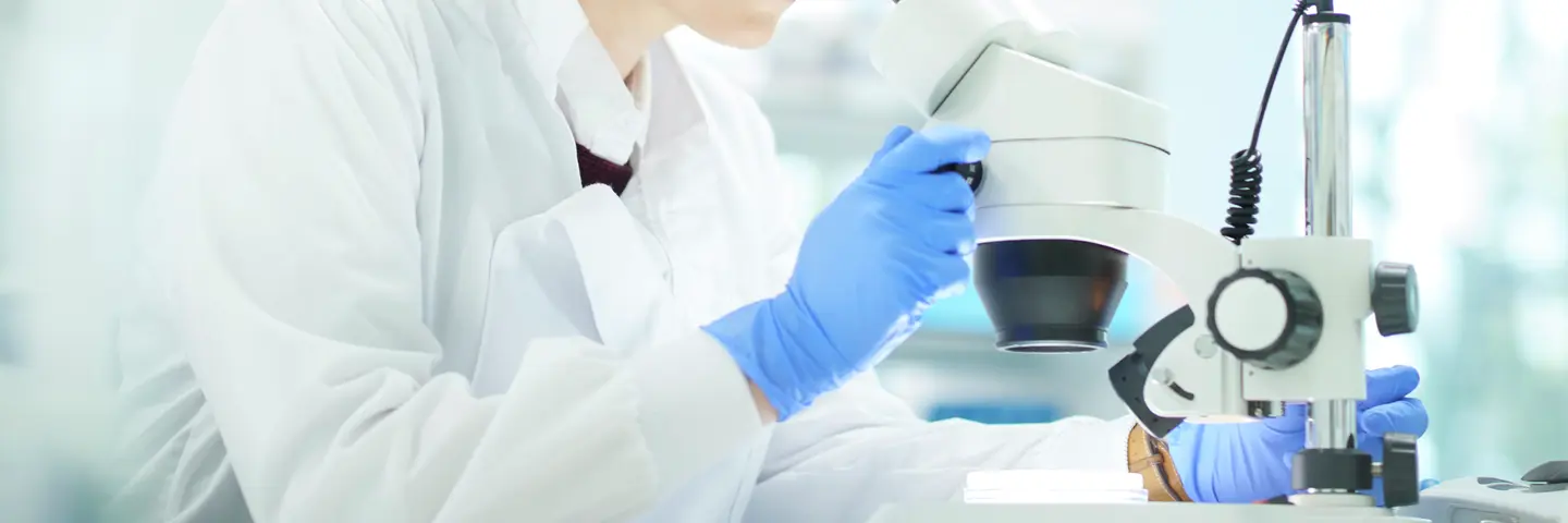 Female scientist in a research lab looking into microscope