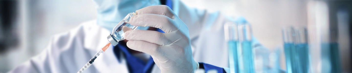 Virologist filling a syringe researching vaccine in laboratory bench