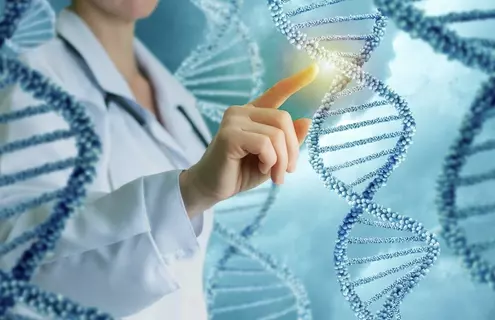 Strands of blue and white-beaded DNA double helixes floating in the air upright, with a woman in a lab coat touching a strand and light illuminating it.