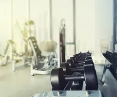 Dumbbells with blurred gym or sport club background at sunset